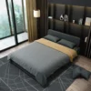 Bambillo Citta Armless Sofa Bed With Headboard in light charcoal colour, showing bed configuration with dark grey doona on bed and two charcoal pillows